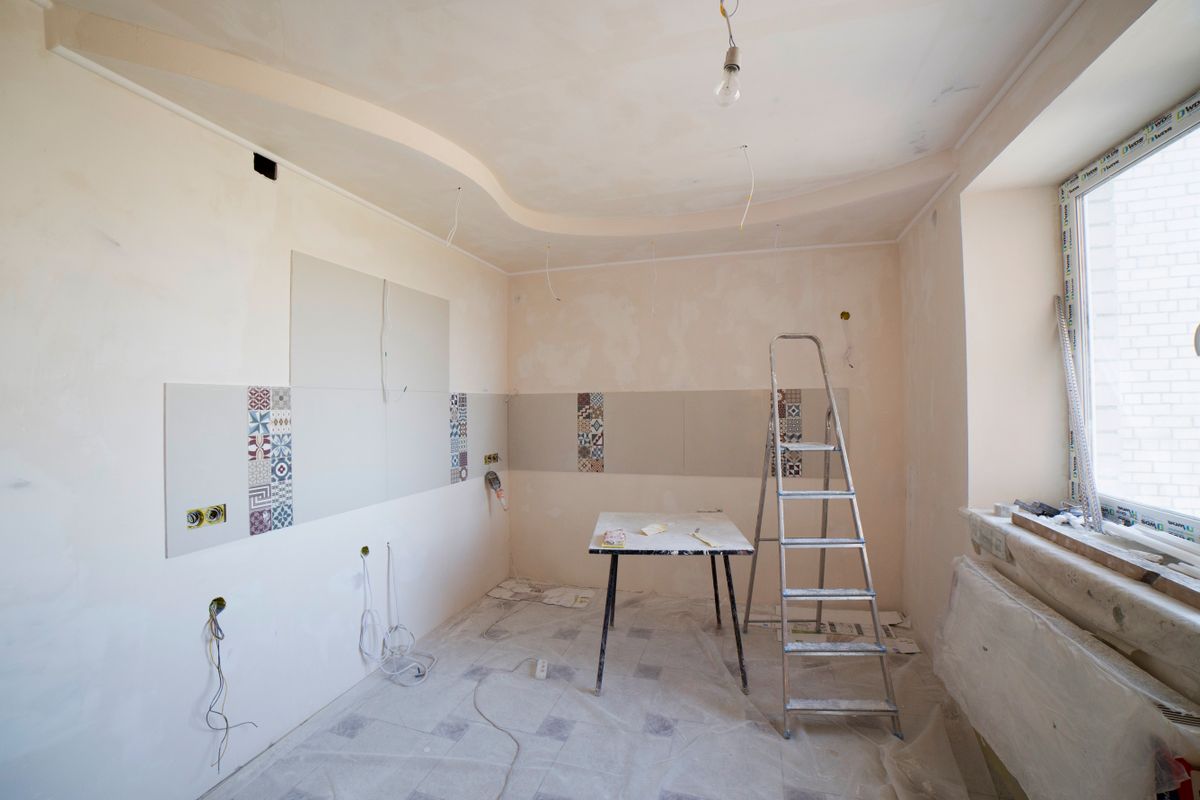 Room mid-renovation with a stepladder, protected floor, and freshly finished ceiling and walls